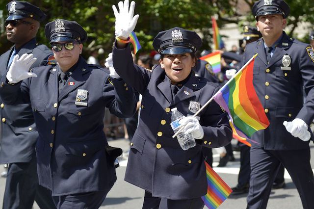 A woman in a New York City Police Department (NYPD) uniform holds a rainbow flag and waves while marching in the annual New York Pride March in 2017.